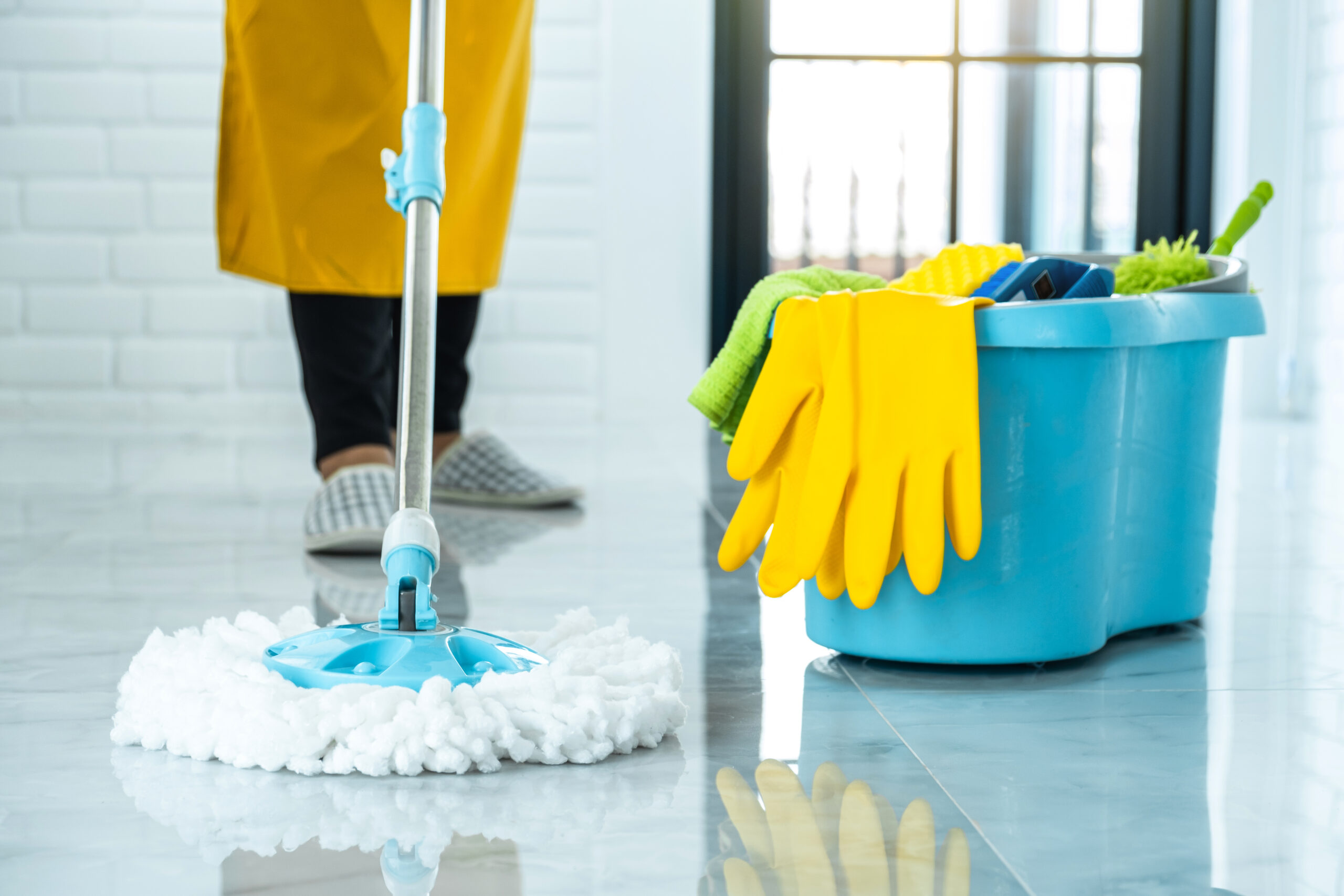 Wife housekeeping and cleaning concept, Happy young woman in blue rubber gloves wiping dust using mop while cleaning on floor at home.